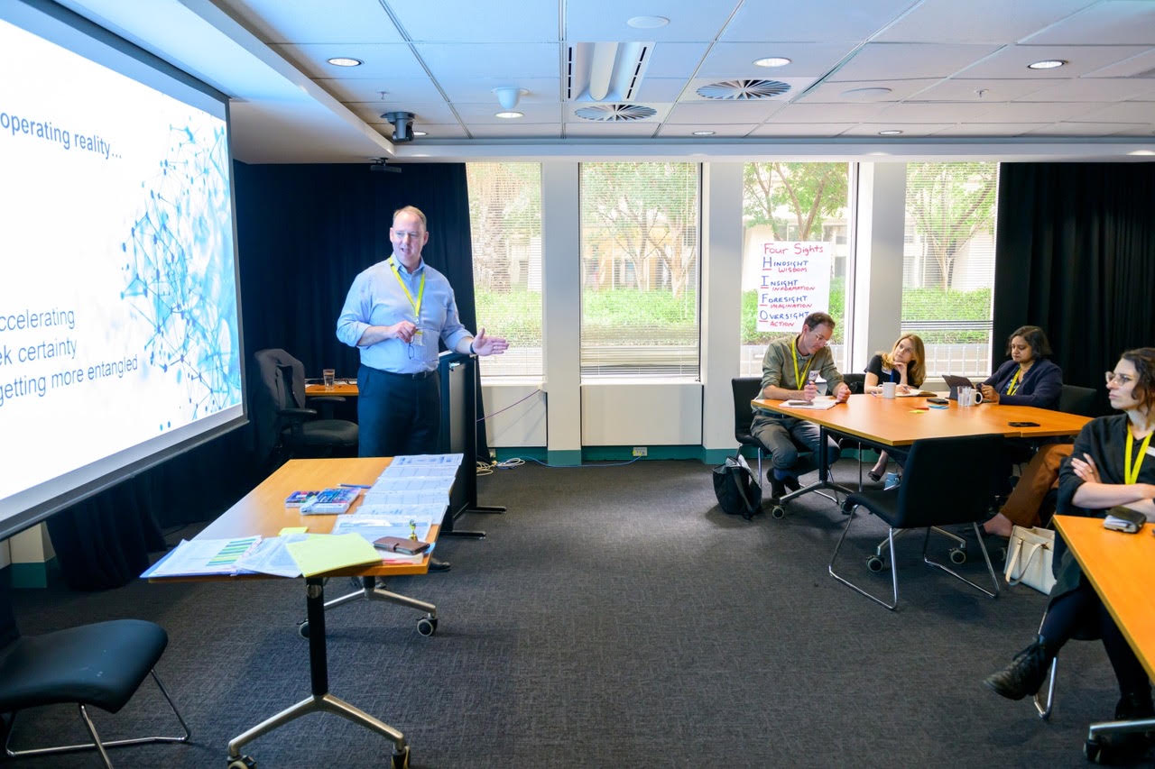 Rob Warner working with participants seated around tables during a regulatory workshop.
